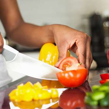 African  American woman's hand slicing a tomatoes